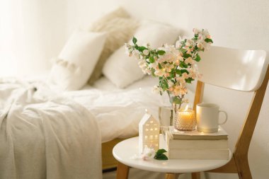 Oturma odasının iç kısımlarında hala hayat detayları var. Kitap, sıcak fincan çayı, mum ve vazo ve elma çiçeği. Oku ve dinlen. Sıcak bahar konsepti.