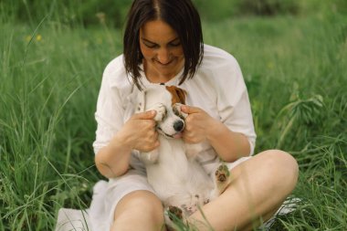 Kadın çayırda Jack Russell Terrier 'cilik oynuyor. Jack Russell Terrier köpeğine sarılan bir kadın. Güzel köpek. Kadın ve köpek dostluğu.
