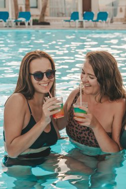 Bir grup güzel genç bayan havuzda dinleniyor. Arkadaşlar bir yaz günü havuzda dinlenir ve gülerler.