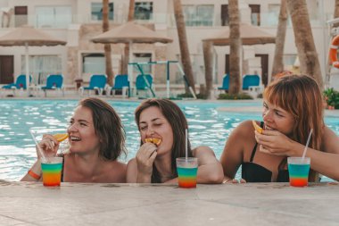 Bir grup güzel genç bayan havuzda dinleniyor. Arkadaşlar bir yaz günü havuzda dinlenir ve gülerler.