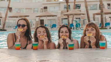 Bir grup güzel genç bayan havuzda dinleniyor. Arkadaşlar bir yaz günü havuzda dinlenir ve gülerler.