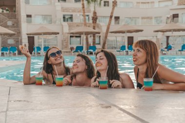 Bir grup güzel genç bayan havuzda dinleniyor. Arkadaşlar bir yaz günü havuzda dinlenir ve gülerler.
