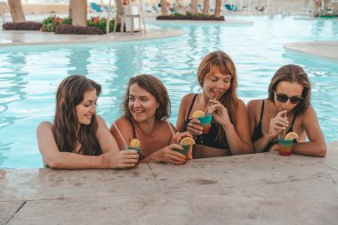 Bir grup güzel genç bayan havuzda dinleniyor. Arkadaşlar bir yaz günü havuzda dinlenir ve gülerler.