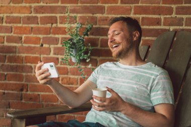 Genç adam telefonda video görüşmesiyle gülüyor ve konuşuyor.. 