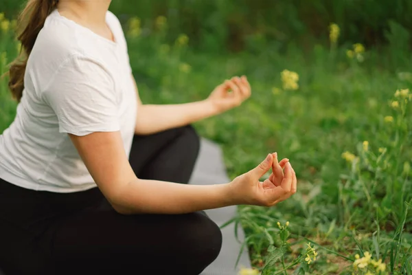 Wanita dengan kaos putih dan legging melakukan yoga di lapangan yang indah di atas matras olahraga. konsep gaya hidup dan kesadaran — Stok Foto