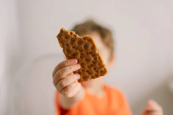 Il ragazzo carino mangia pane croccante. Stile di vita sano e concetto di nutrizione. — Foto Stock