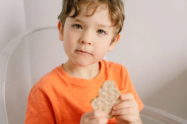 Il ragazzo carino mangia pane croccante. Stile di vita sano e concetto di nutrizione. — Foto Stock