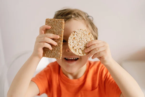 Il ragazzo carino mangia pane croccante. Stile di vita sano e concetto di nutrizione. — Foto Stock