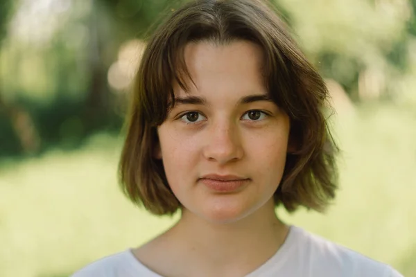 Hermosa joven adolescente chica con un pelo bob de moda en una camiseta blanca en un exterior y mirando a la cámara. — Foto de Stock