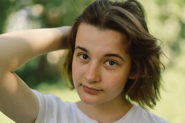 Hermosa joven adolescente chica con un pelo bob de moda en una camiseta blanca en un exterior y mirando a la cámara. — Foto de Stock