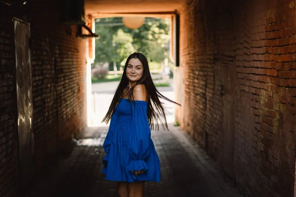 Портрет щасливої молодої жінки в блакитній сукні сміється, дивлячись на камеру, що стоїть на вулиці. Міське тло — стокове фото