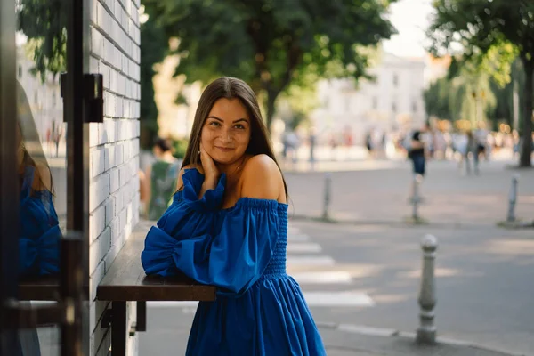 Retrato feliz jovem mulher vestindo vestido azul rindo olhando para a câmera de pé na rua. Fundo urbano — Fotografia de Stock