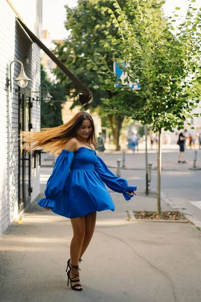 Portré boldog fiatal nő kék ruhát visel nevetett a kamerába állt az utcán. Városi háttér — Stock Fotó