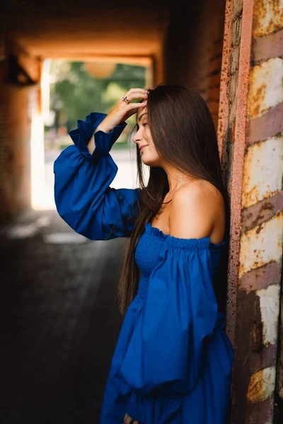 Портрет щасливої молодої жінки в блакитній сукні сміється, дивлячись на камеру, що стоїть на вулиці. Міське тло — стокове фото