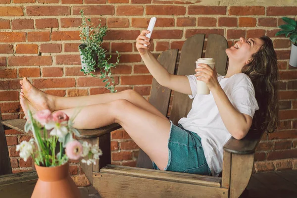 Jonge vrouw lacht en praat per videogesprek aan de telefoon. Het concept van levensstijl mobiliteit — Stockfoto