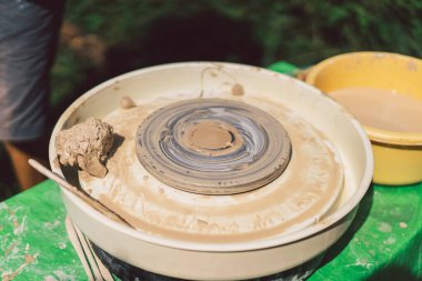 Potter dışarıda çömlek çarkında kilden bir nesne yapıyor. El sanatları ustası çömlek çarkında elleri olan kil şekillendiriyor.