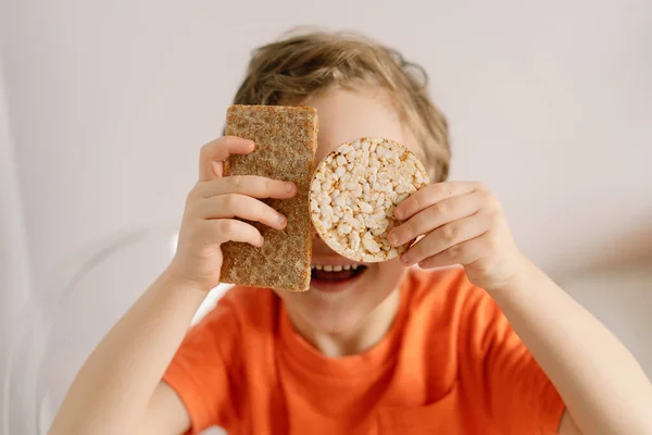 Il ragazzo carino mangia pane croccante. Stile di vita sano e concetto di nutrizione. — Foto Stock