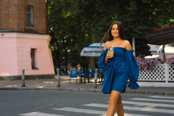 파란 드레스를 입고 여름 칵테일 레모네이드를 마시는 행복 한 젊은 여성의 초상화 — 스톡 사진