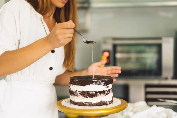Кондитерша готовит пирожное с белым кремом и шоколадом. Кулинарные торты. — стоковое фото