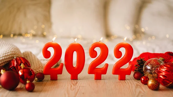 Szczęśliwego Nowego Roku 2022. Numery roku 2022 wykonane przez czerwone świece na bokeh świąteczne musujące tło — Zdjęcie stockowe