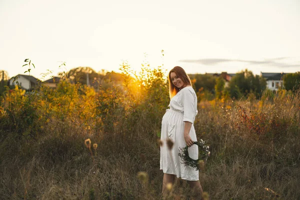 一个孕妇的画像 一个穿着白衣的漂亮的年轻孕妇在田野里散步 祝你怀孕愉快怀孕的概念 浪漫的心情 自然情人 — 图库照片