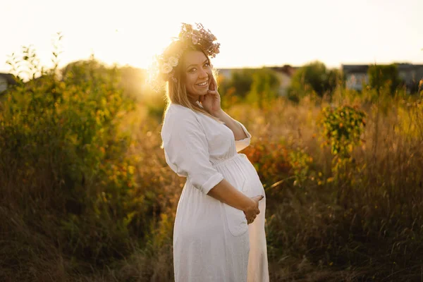 Portrait d'une femme enceinte. Une belle jeune femme enceinte en robe blanche se promène dans les champs. — Photo