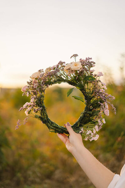 Summer lifestyle portrait of beautiful young woman in a wreath of wild flowers. Wreath on his head