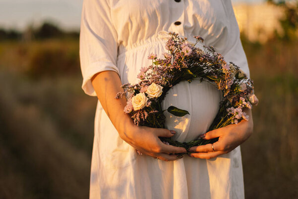Portrait of a pregnant woman. A beautiful young pregnant woman in a white dress walks in the field. Happy pregnancy. Concepts of pregnancy. Romantic mood. Nature lover.