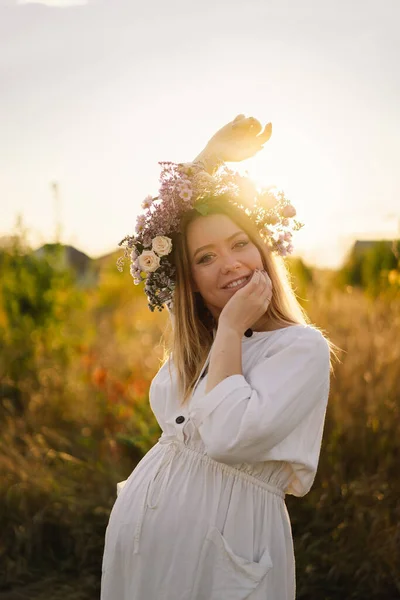 Portrait of a pregnant woman. A beautiful young pregnant woman in a white dress walks in the field. — Stock Photo, Image