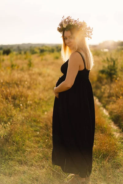 Porträtt av en gravid kvinna. En vacker ung gravid kvinna i vit klänning går i fält. — Stockfoto
