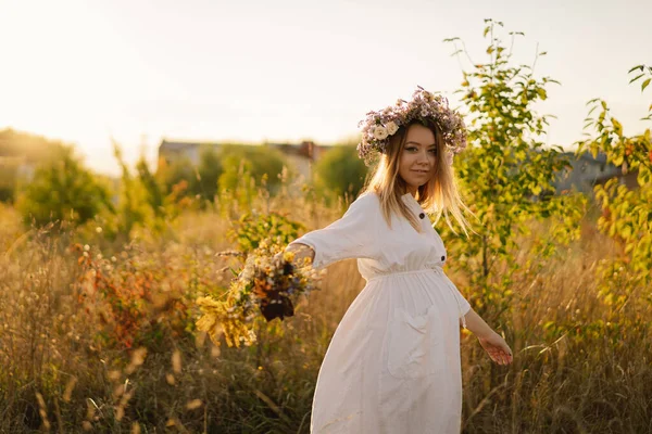 Egy terhes nő portréja. Egy gyönyörű, fiatal, fehér ruhás terhes nő sétál a mezőn.. — Stock Fotó