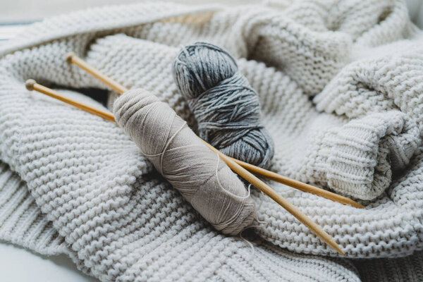 Knitting tools and various yarn balls are arranged on a soft, textured blanket, creating a warm, inviting atmosphere for crafting.