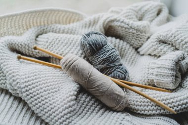 Knitting tools and various yarn balls are arranged on a soft, textured blanket, creating a warm, inviting atmosphere for crafting.