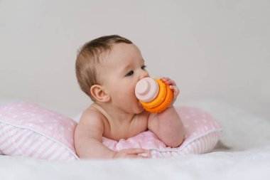 Bebek yumuşak bir yastığa uzanır, renkli bir oyuncağa uzanır. Erken çocukluk gelişimi, ebeveynlik bakımı, mutlu aile anları ve bebek yaşam tarzı kavramı.