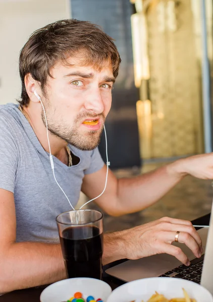 Um homem a trabalhar no computador e a comer fast food. Vida não saudável — Fotografia de Stock