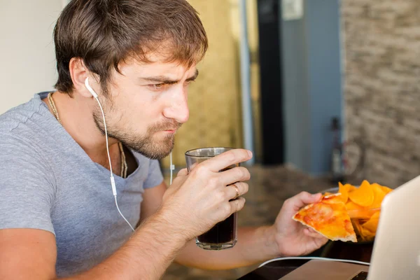 Um homem a trabalhar no computador e a comer fast food. Vida não saudável — Fotografia de Stock