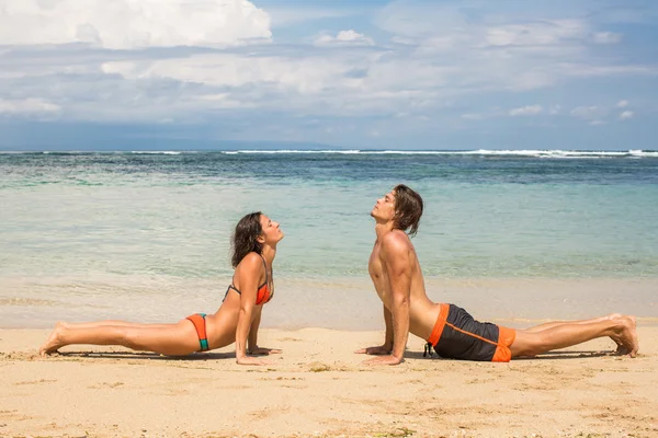 Dvojice dělat cvičení jógy a relaxace u moře — Stock fotografie
