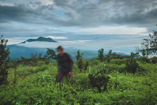 Man is zittend op de heuvel en kijken op de vulkaan Batur in Bali — Stockfoto