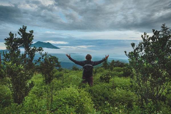 Homem está sentado na colina e olhando para o vulcão Batur em Bali — Fotografia de Stock