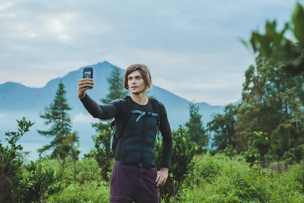 Tourist takes a snapshot by smarphone of the Batur volcano from — Stock Photo, Image