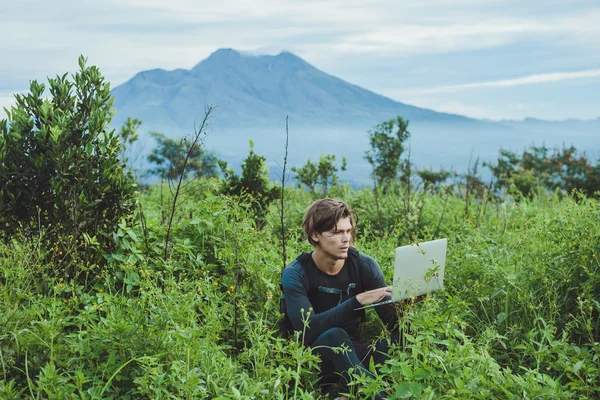 Homem trabalhando com laptop no topo da montanha com bela la — Fotografia de Stock