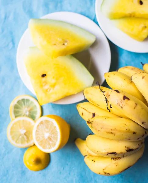 Bananas, melancia e amarelo limão em uma mesa azul — Fotografia de Stock