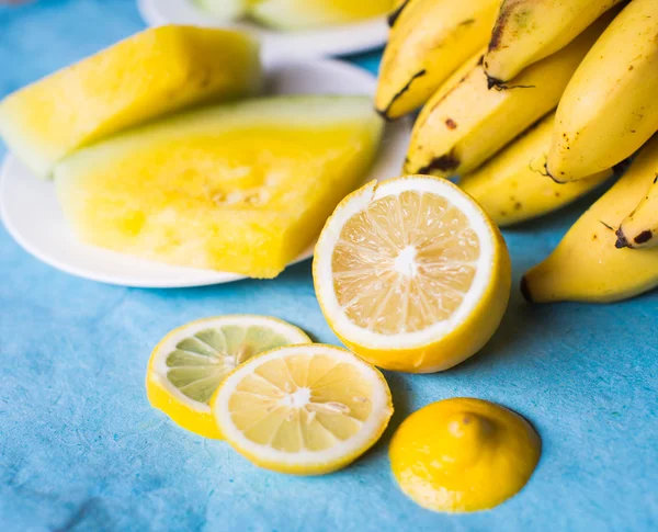Bananas, melancia e amarelo limão em uma mesa azul — Fotografia de Stock