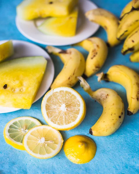 Bananas, watermelon and lemon yellow on a blue table
