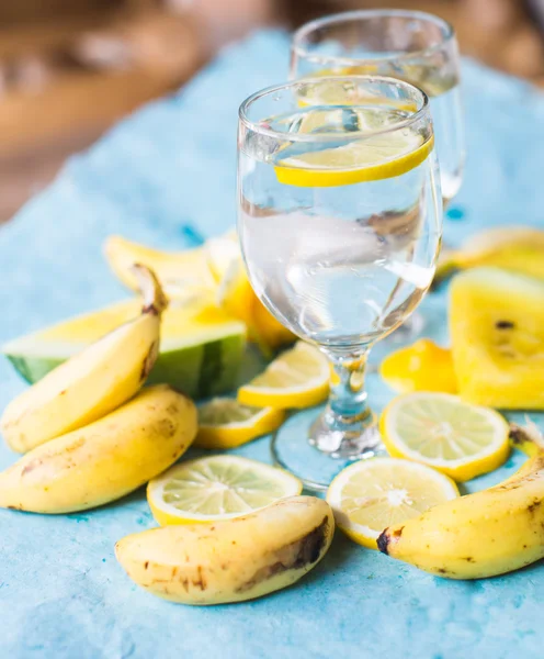 Agua de desintoxicación con frutas amarillas sobre fondo azul — Foto de Stock