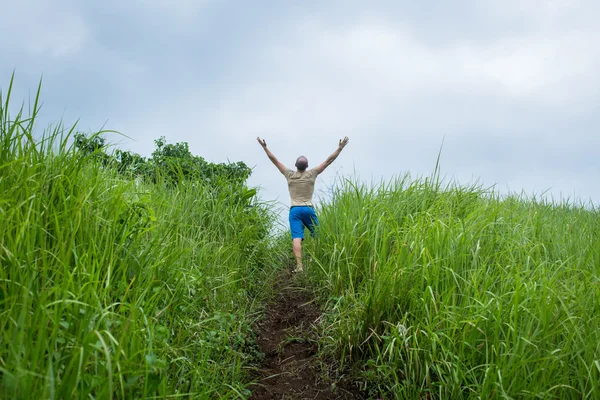 Jovem no campo levantando as mãos — Fotografia de Stock