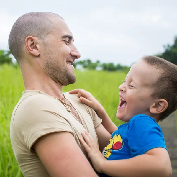Joven padre feliz sosteniendo en sus brazos pequeño hijo —  Fotos de Stock