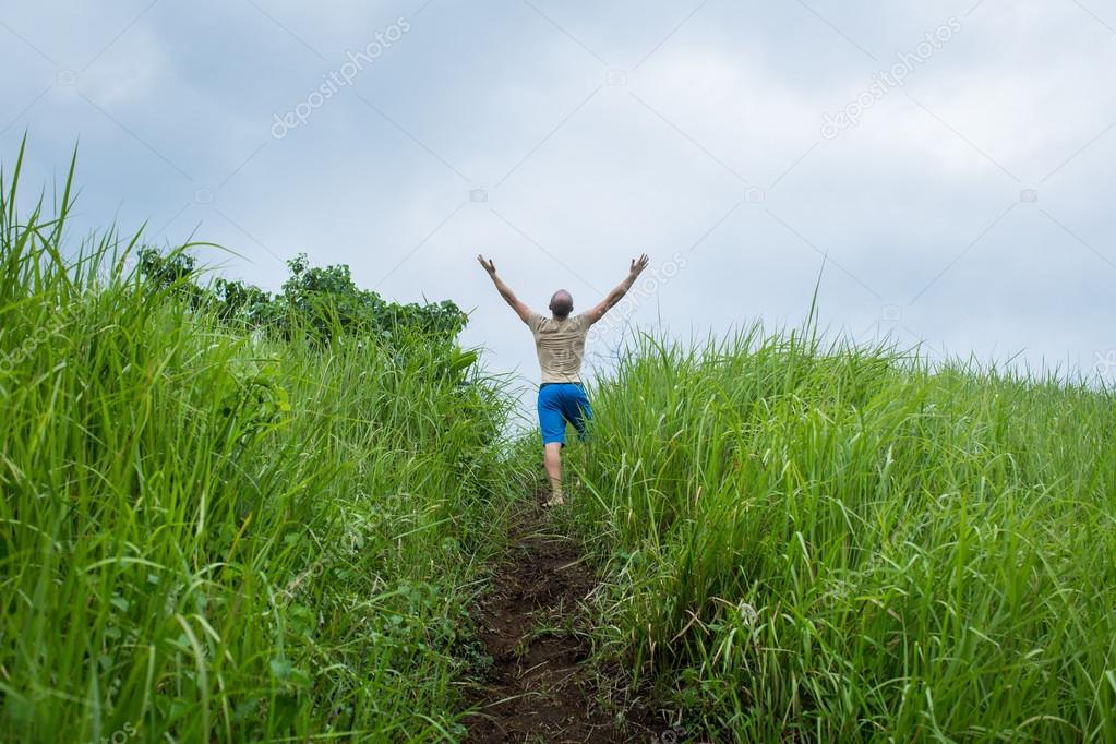 Young Man at Field rising up the Hands