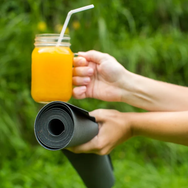 Свежий апельсиновый сок и коврик для йоги на траве — стоковое фото