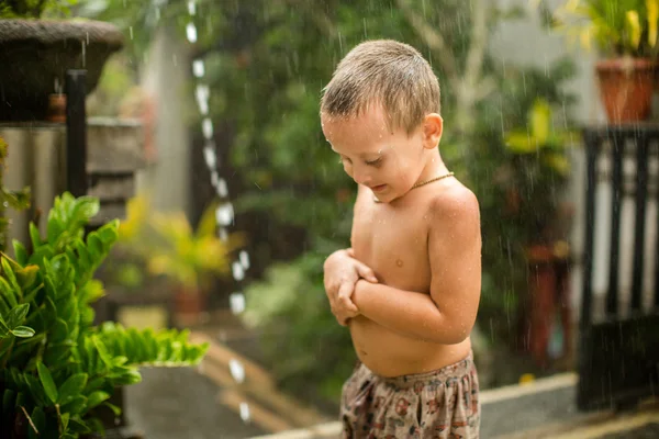 Милый мальчик играет под дождем — стоковое фото